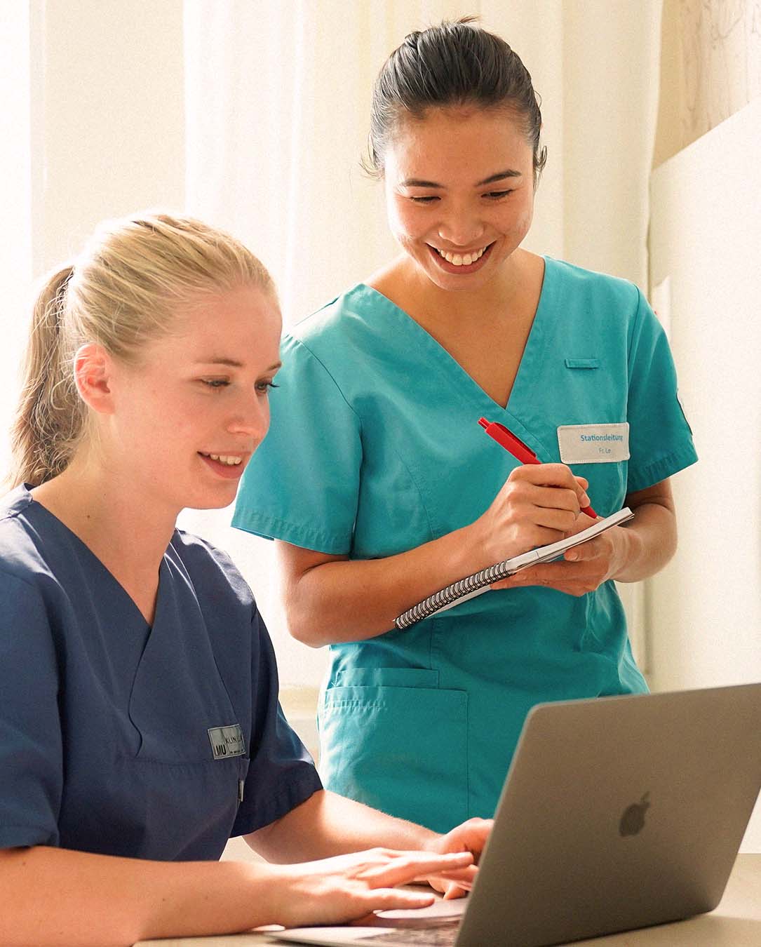 Zwei Pflegekräfte sehen sich etwas in einem Laptop an